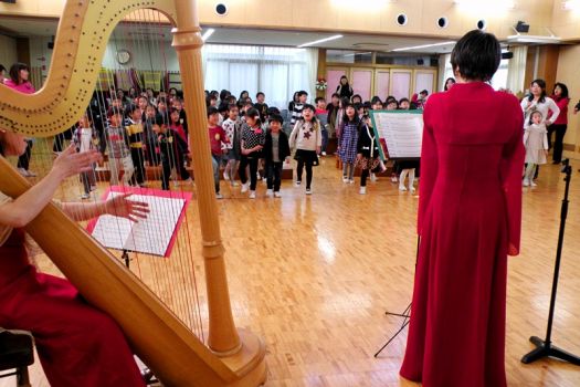 演奏に合わせ、足踏みをしながら 『ゆかいに歩けば』を歌う子ども達