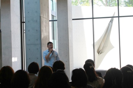 中学校高等学校校舎に設置された彫刻のお披露目会で作品を前に語る高橋智力さん（2017年5月）