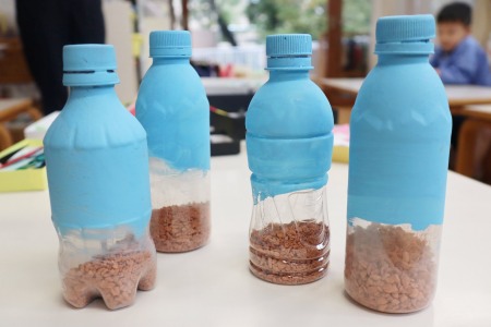 前半はペットボトルに土を入れて絵具で色付け。 後半はここから飾りをつけていきます。