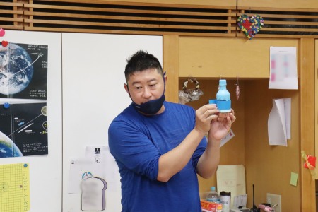 「好きな色の紙をかさねてペットボトルに貼ってみよう」と高橋先生。