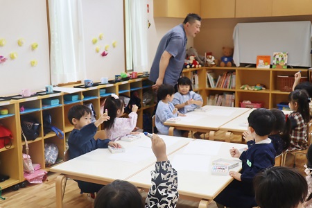 「今一番好きな色は？」 先生の質問に好きな色のクレヨンを掲げて先生に知らせます